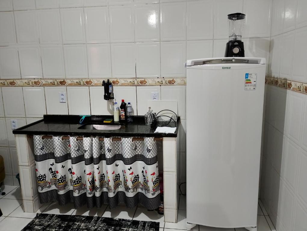 a kitchen with a counter with a sink and a refrigerator at Casa com 1 cama de casal e 1 cama de solteiro in Serra