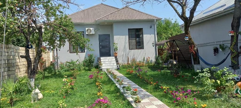 a small white house with a yard with flowers at Qabala Villa in Gabala