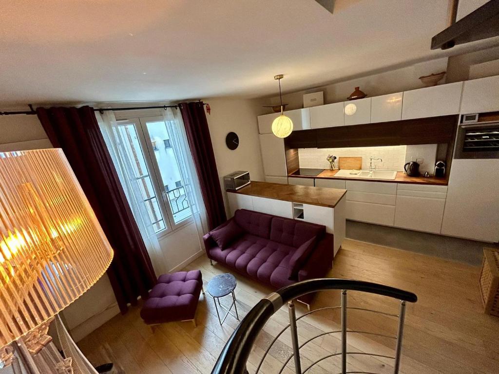 a living room with a purple couch and a kitchen at Joli Duplex Confort T2 Paris Porte De Versailles in Vanves