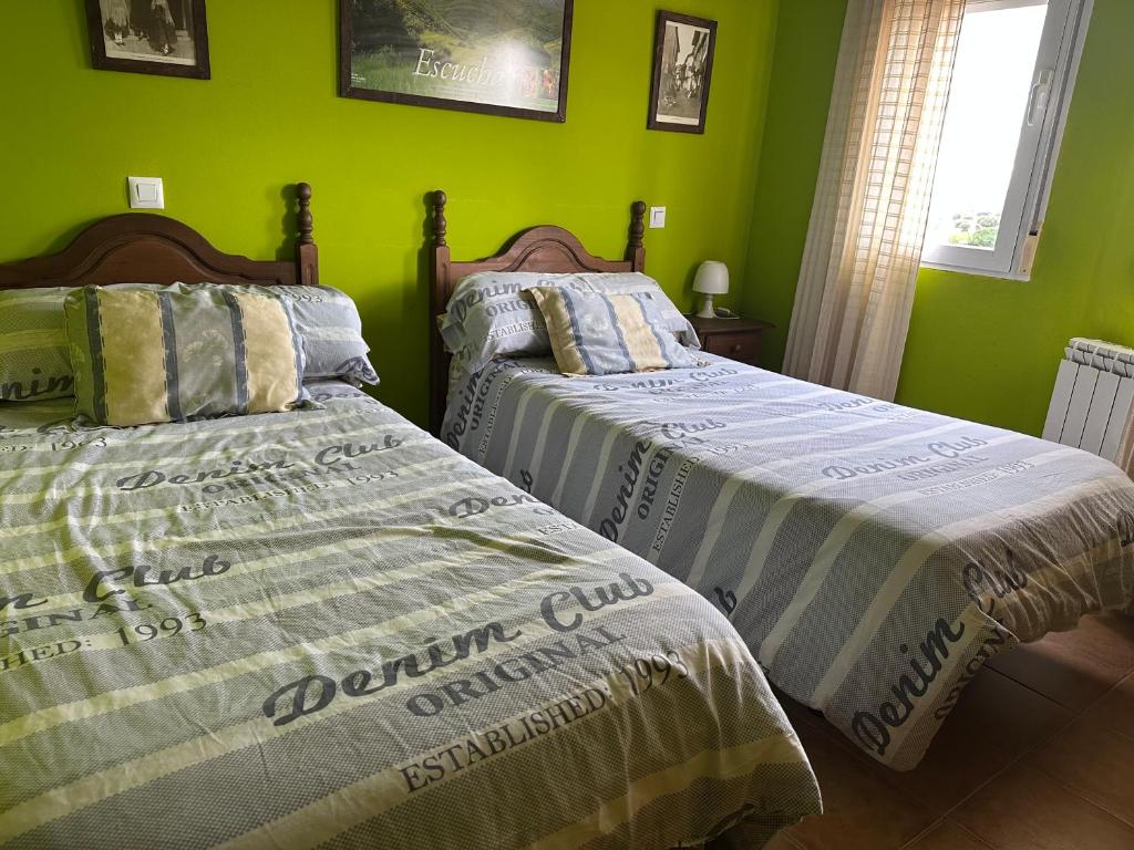 two beds in a room with green walls at Casas Encinares in Narrillos de San Leonardo