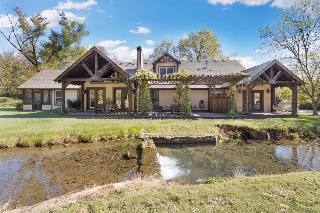 a house with a river in front of it at Whispering Brook in Springdale