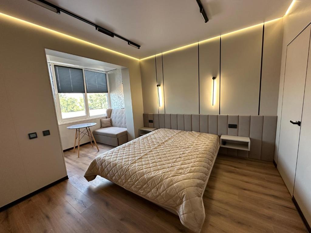 a bedroom with a bed and a table and a window at Видова смарт-квартира в ЖК City Park in Cherkasy