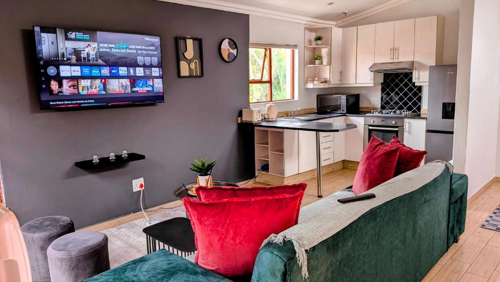 a living room with a couch and a tv on the wall at Luxury Studio in Fourways in Sandton