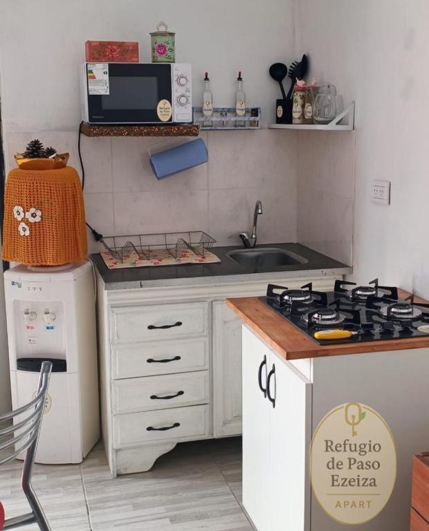 a small kitchen with a stove and a sink at Refugio de Paso Ezeiza in Ezeiza