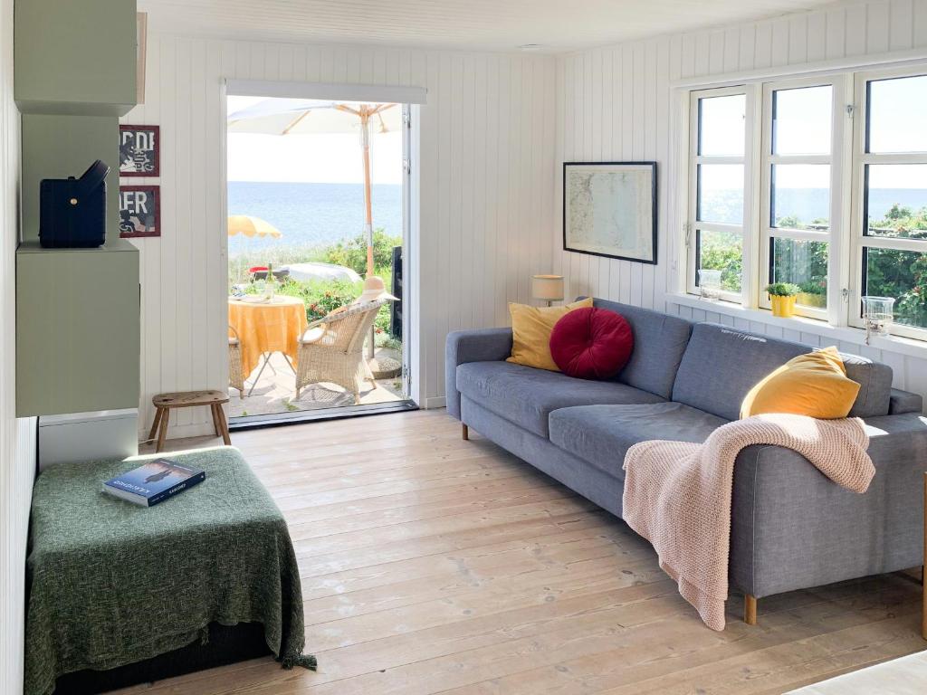 a living room with a blue couch and a view of the ocean at Beachfront House At Hølken Beach in Odder