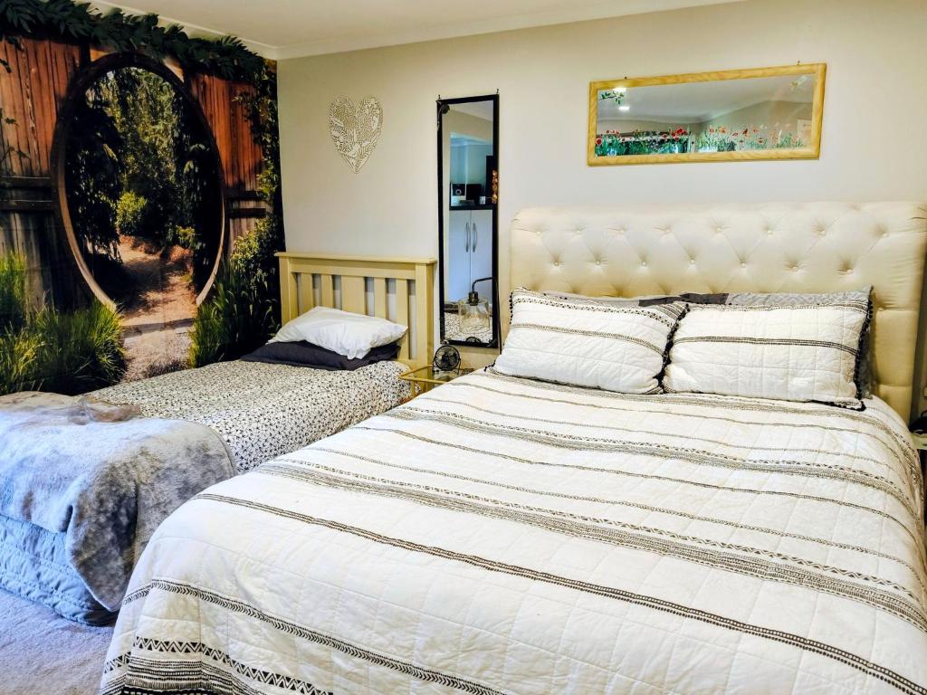 a bedroom with two beds and a mirror at Escape to Tranquility in Rotoruas Heart in Mourea