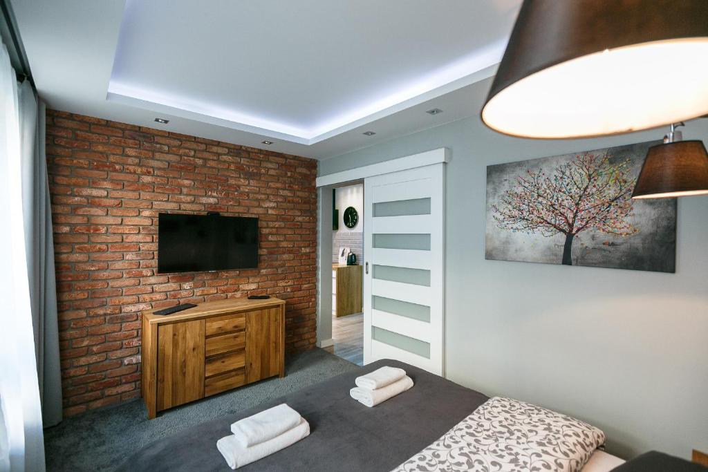 a bedroom with a brick wall and a television at Apartament eM klimatyzacja&parking in Rzeszów