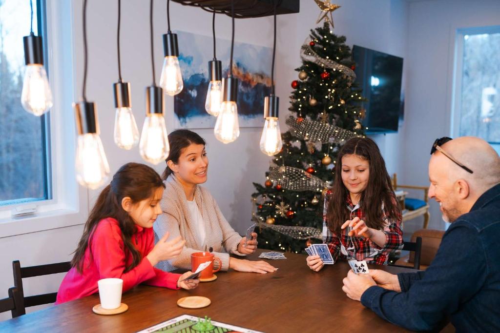 Una familia sentada alrededor de una mesa con un árbol de Navidad en Le Yéti de Tremblant, en La Conception
