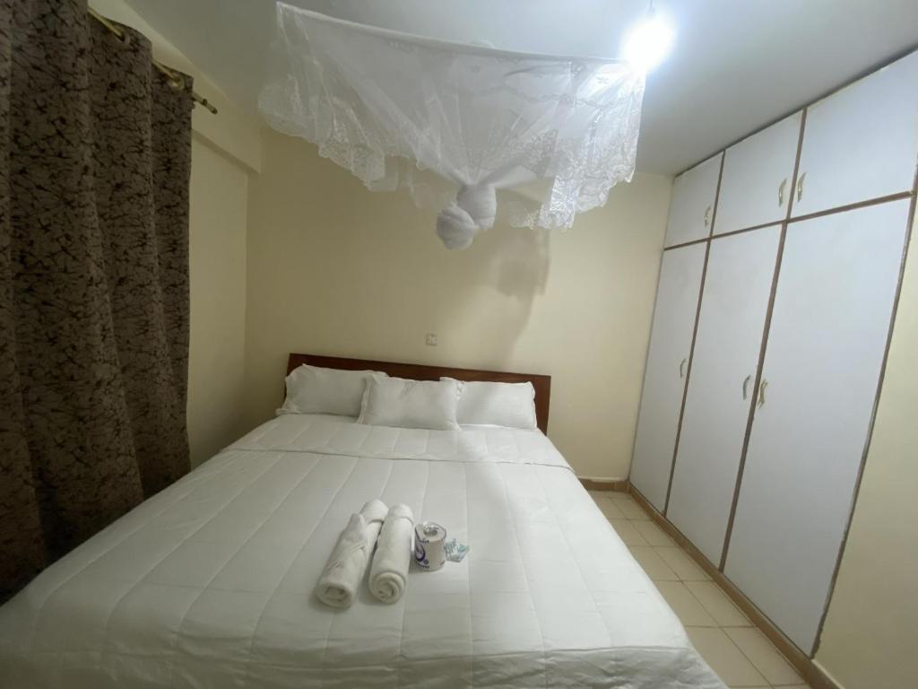 J and A Haven BnB- Langata Road opposite Uhuru gardens memorial park في نيروبي: غرفة نوم بسرير ابيض عليها مناشف