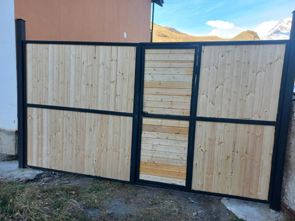 a wooden fence with two doors in front of a house at Sesili's apartment in Stepantsminda