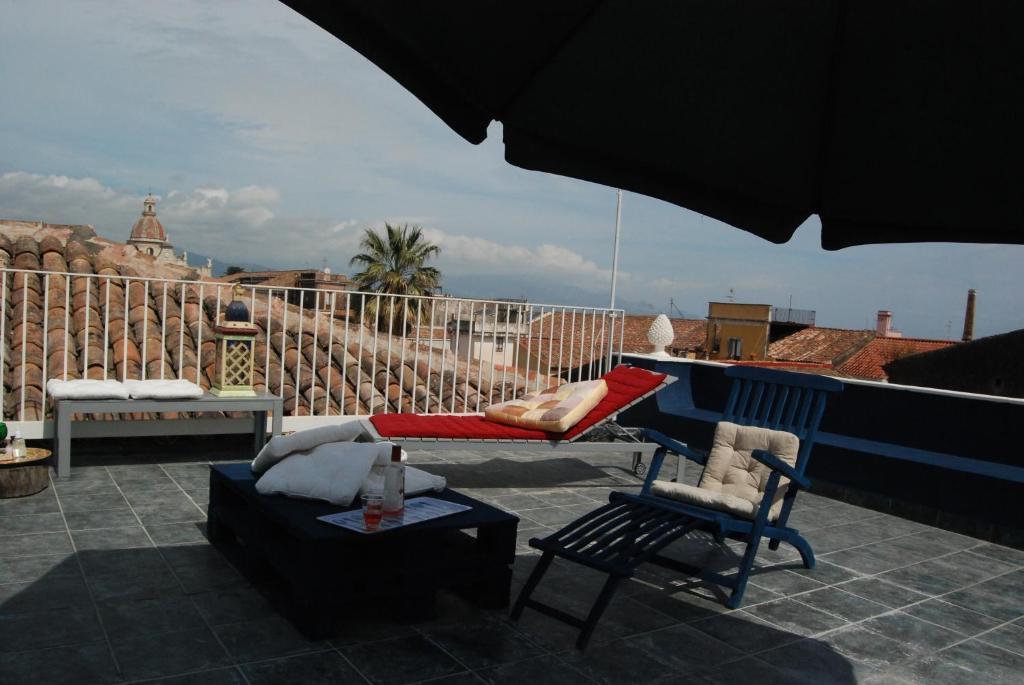 a patio with a couch and a chair and an umbrella at Kemmare in Riposto