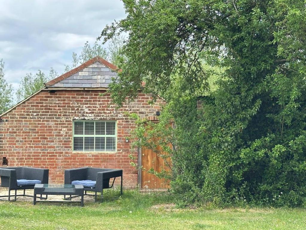 Un edificio de ladrillo con dos bancos y una mesa. en Tranquil detached barn in Sherborne St John, en Sherborne Saint John