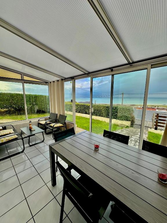 a living room with a wooden table and a large window at Le Cottage de la Baie - vue mer en Baie de Somme in Woignarue