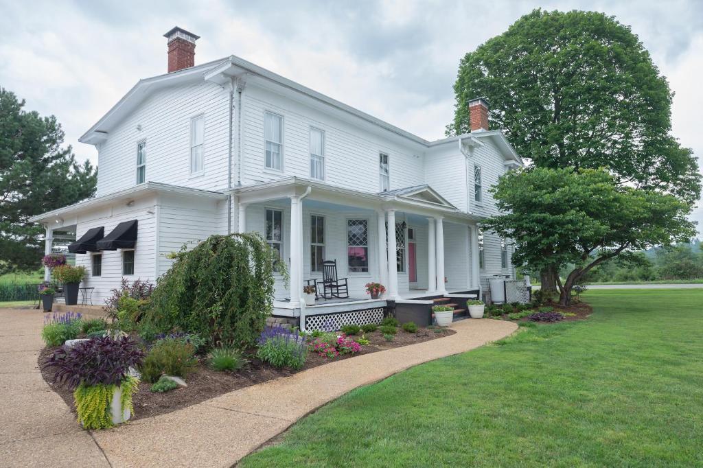 a white house with a lawn and flowers at Old Furnace Inn in Harrisonburg