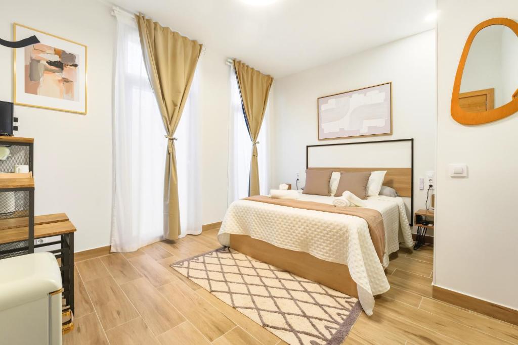 ein weißes Schlafzimmer mit einem Bett und einem Spiegel in der Unterkunft Casa Príncipe Pío in Madrid