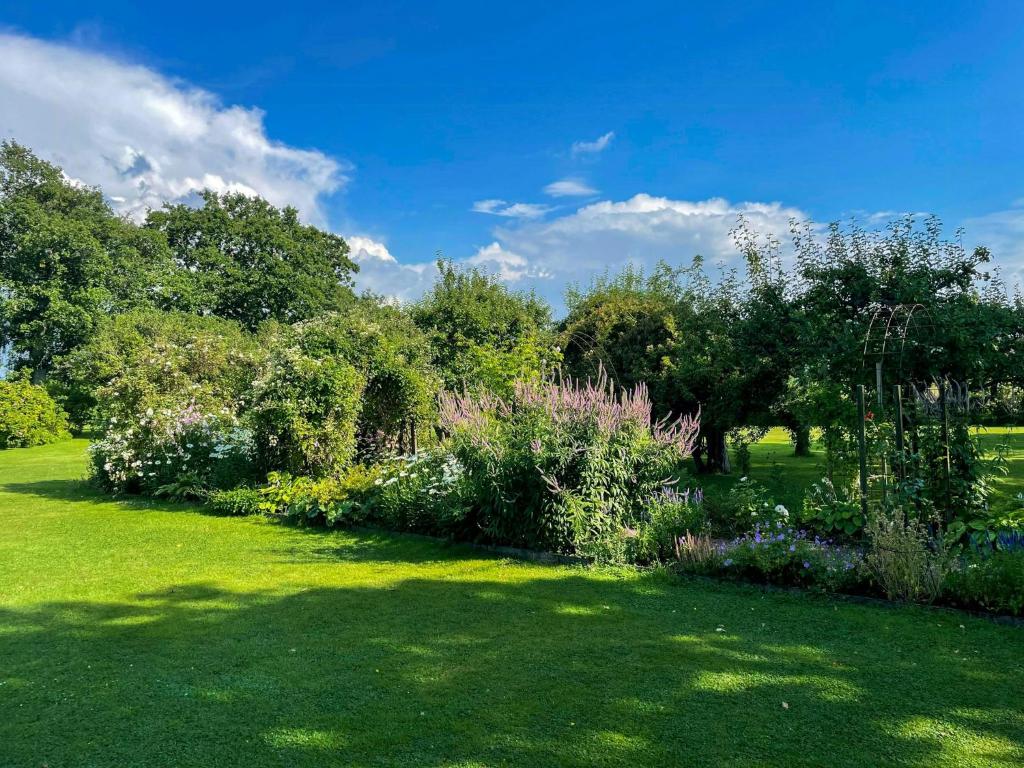 Un jardín con flores y árboles en un campo verde. en Historic Halland Farm Near The Sea In Bua, en Väröbacka