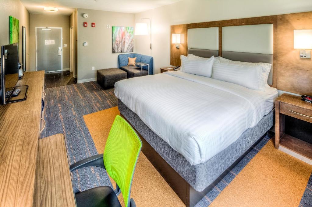 a hotel room with a large bed and a chair at Holiday Inn Express & Suites Cleveland/Westlake by IHG in Westlake