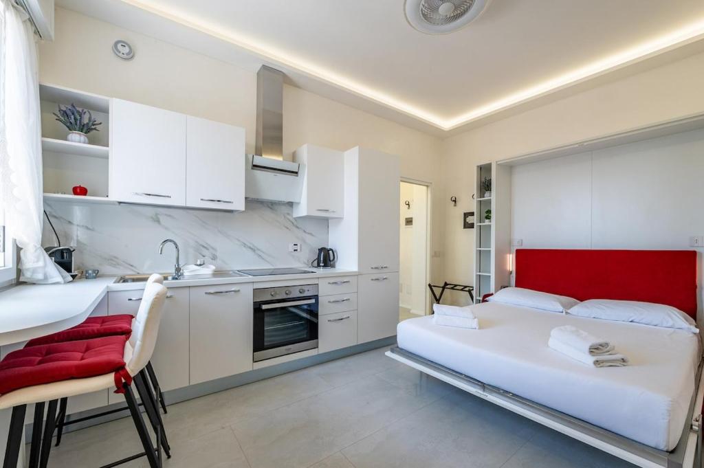 a bedroom with a bed and a kitchen with white cabinets at Harmony's Nest - Vicino a treno e Fiera Milano in Rho