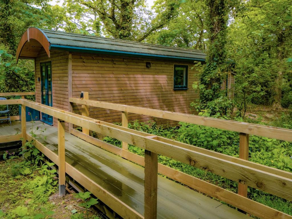 eine Hütte im Wald mit einem Holzzaun in der Unterkunft Woodpecker - Uk43451 in Hayle