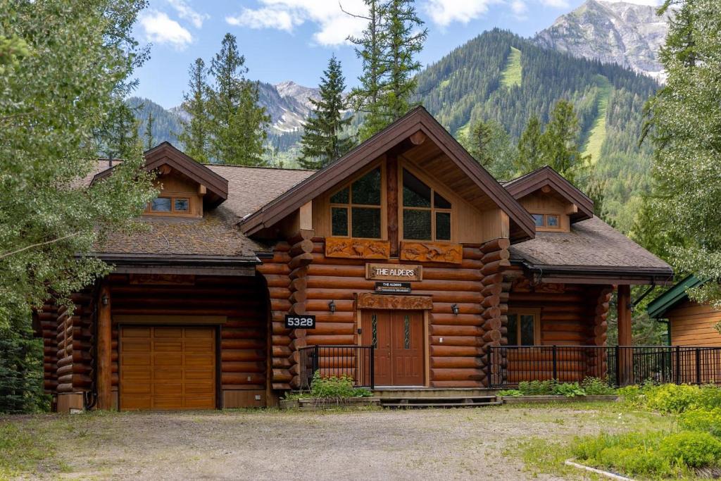 a log cabin with mountains in the background at Alders Chalet by Fernie Central Reservations in Fernie