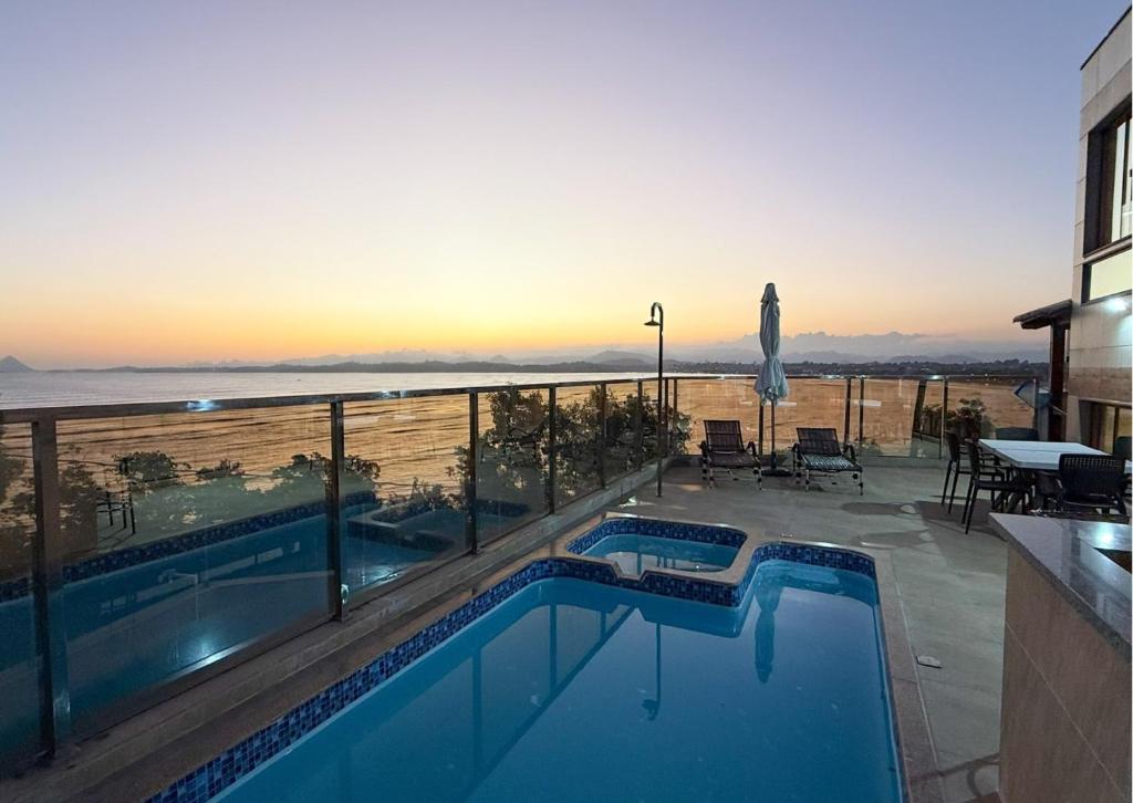 a swimming pool with a view of the ocean at Luxo Frente Mar em 7 Qtos com Ar sendo 4 suites para até 18 pessoas, 2 Jacuzzi Aquecidas, piscina, brinquedoteca, 5min de Castelhanos in Anchieta
