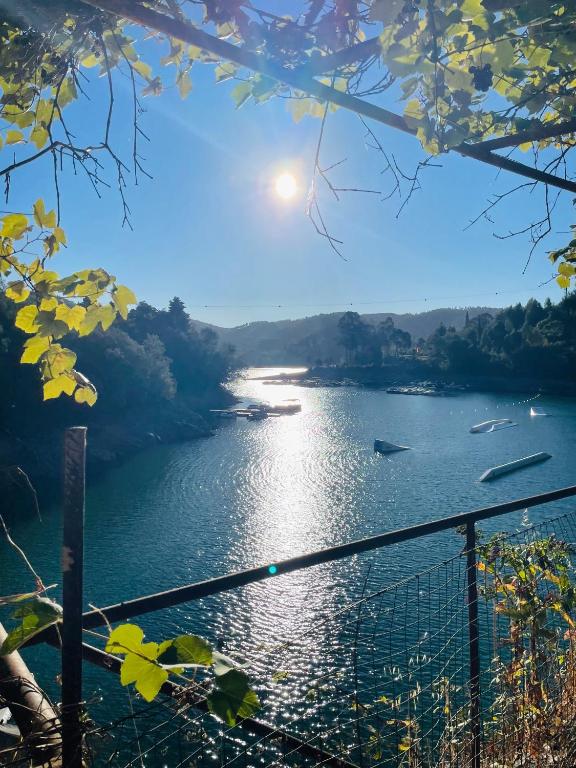 a view of a river with the sun in the sky at Casinha do Lago in Ferreira do Zêzere