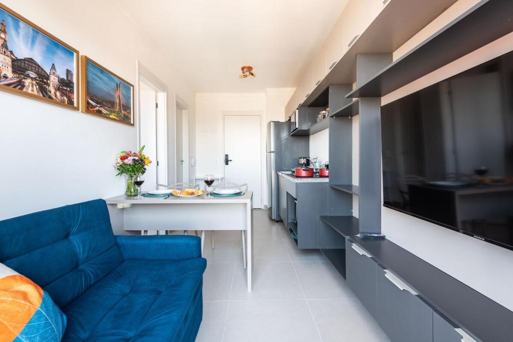 a living room with a blue couch and a kitchen at Apto Novo Centro SP Com Vista Panorâmica in Sao Paulo