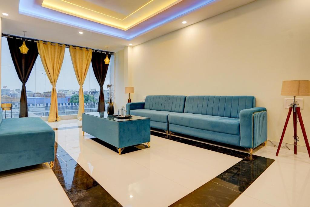 ein Wohnzimmer mit einem blauen Sofa und einem Tisch in der Unterkunft HOTEL O GS GALAXY in Kānpur
