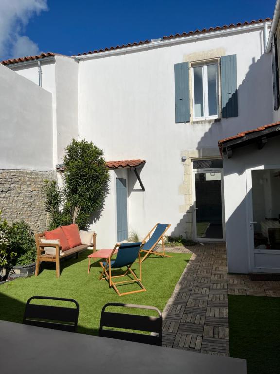 een tuin met twee stoelen en een bank bij Location Ile d'Oléron, plage et commerces à pieds in Le Château-dʼOléron