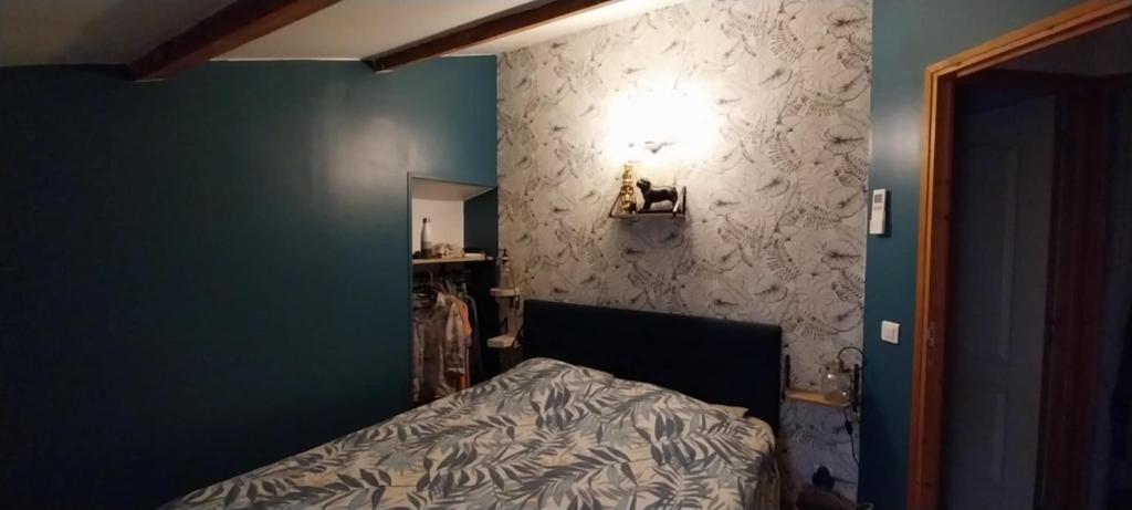 a bedroom with a bed and a green wall at A L ESCALE PASSA PAÏS in Le Poujol-sur-Orb