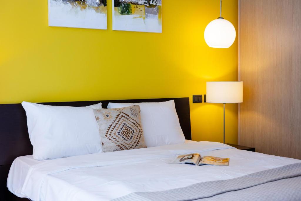 ein Schlafzimmer mit einem weißen Bett und einer gelben Wand in der Unterkunft Yerevan Elite Stay - Republic Square in Yerevan