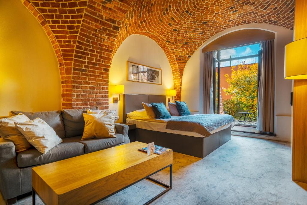 a living room with a couch and a bed at Great Polonia The Granary La Suite Hotel in Wrocław
