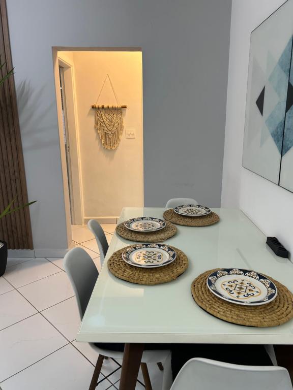 une table avec quatre plaques au-dessus dans l'établissement Apartamento em Santos no Gonzaga em frente a praia, à Santos