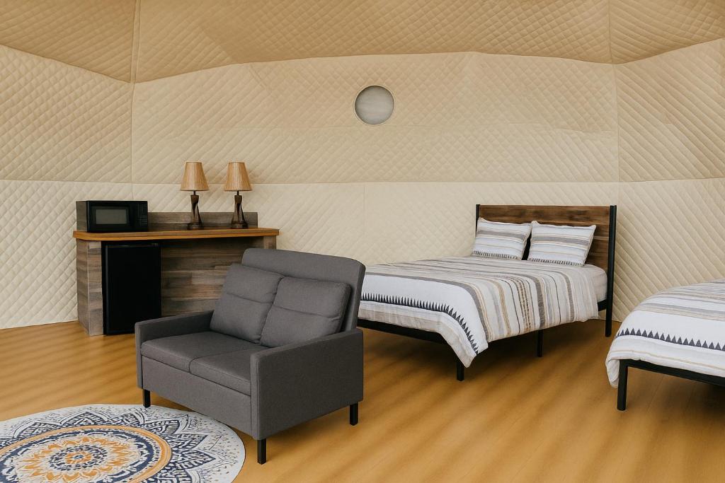 a bedroom with two beds and a chair in it at Baddeck Domes in Baddeck