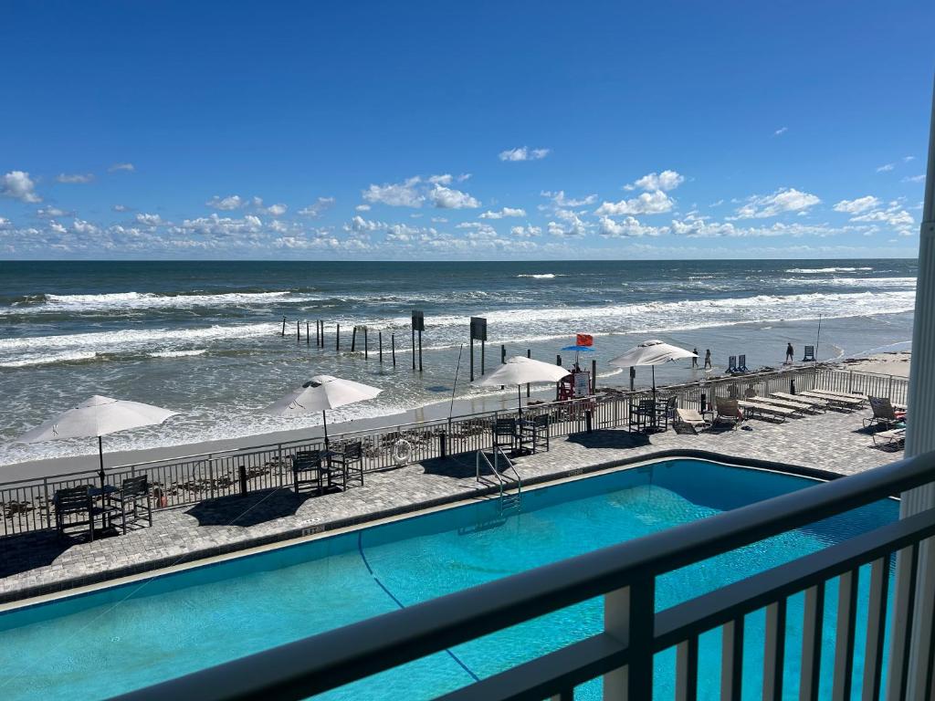 a view of a swimming pool and the beach at Daytona Inn in Daytona Beach
