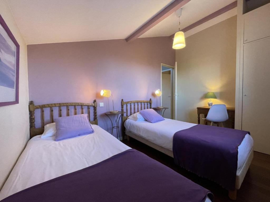 zwei Betten in einem Hotelzimmer mit lila Laken in der Unterkunft Ohiana in Villefranque