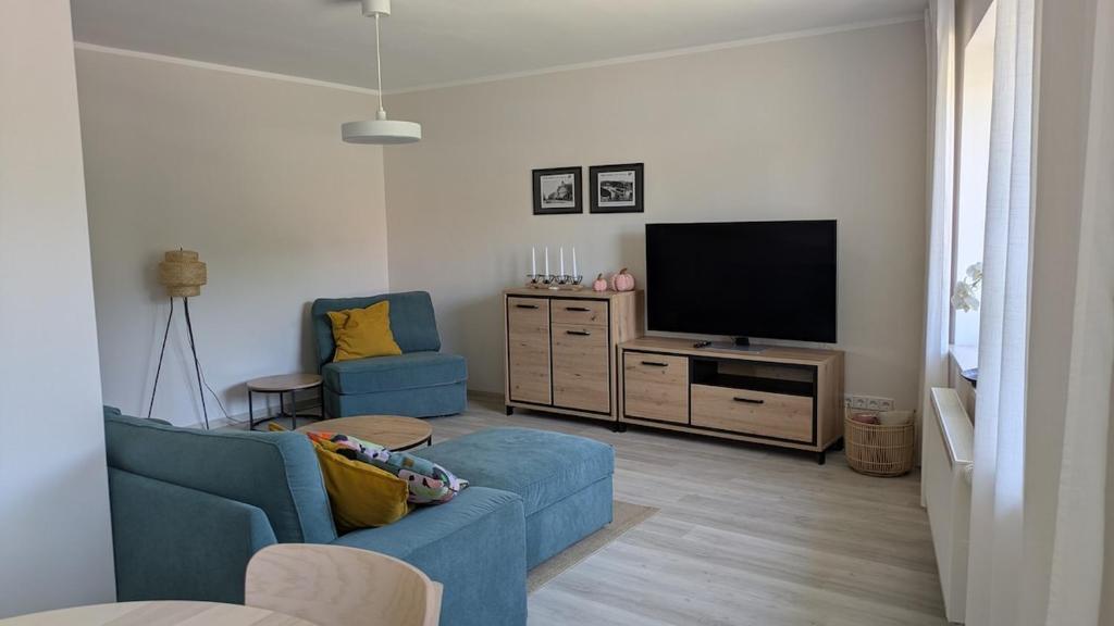 a living room with a blue couch and a flat screen tv at Moderne 3-Zimmer-Ferienwohnung direkt am Saaleradwanderweg in Halle an der Saale