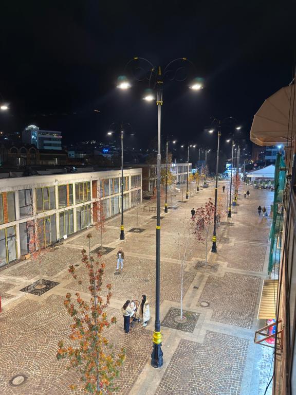 eine Straße bei Nacht mit Menschen, die auf einem Bürgersteig gehen in der Unterkunft Mountain View Apartment in the heart of city in Peja