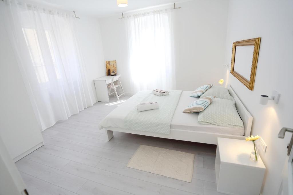 a white bedroom with a large bed and a mirror at Contarini Apartment in Split