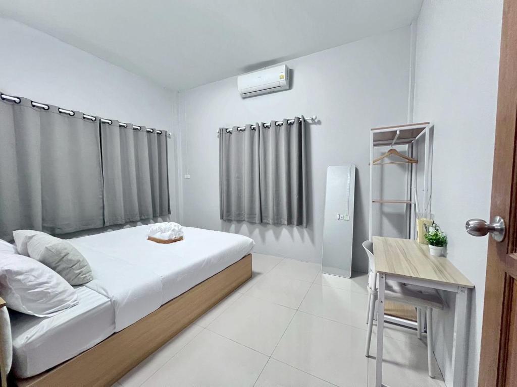 a bedroom with a bed and a table and a refrigerator at I'm Home Narathiwat in Narathiwat