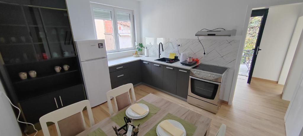 a kitchen with black cabinets and a table with chairs at Anna apartman in Niš