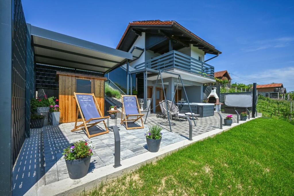 een huis met een patio met 2 stoelen en bloemen bij View&Wine in Veliko Trgovišće