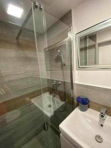 a bathroom with a glass shower and a sink at O5 residence in Nivy