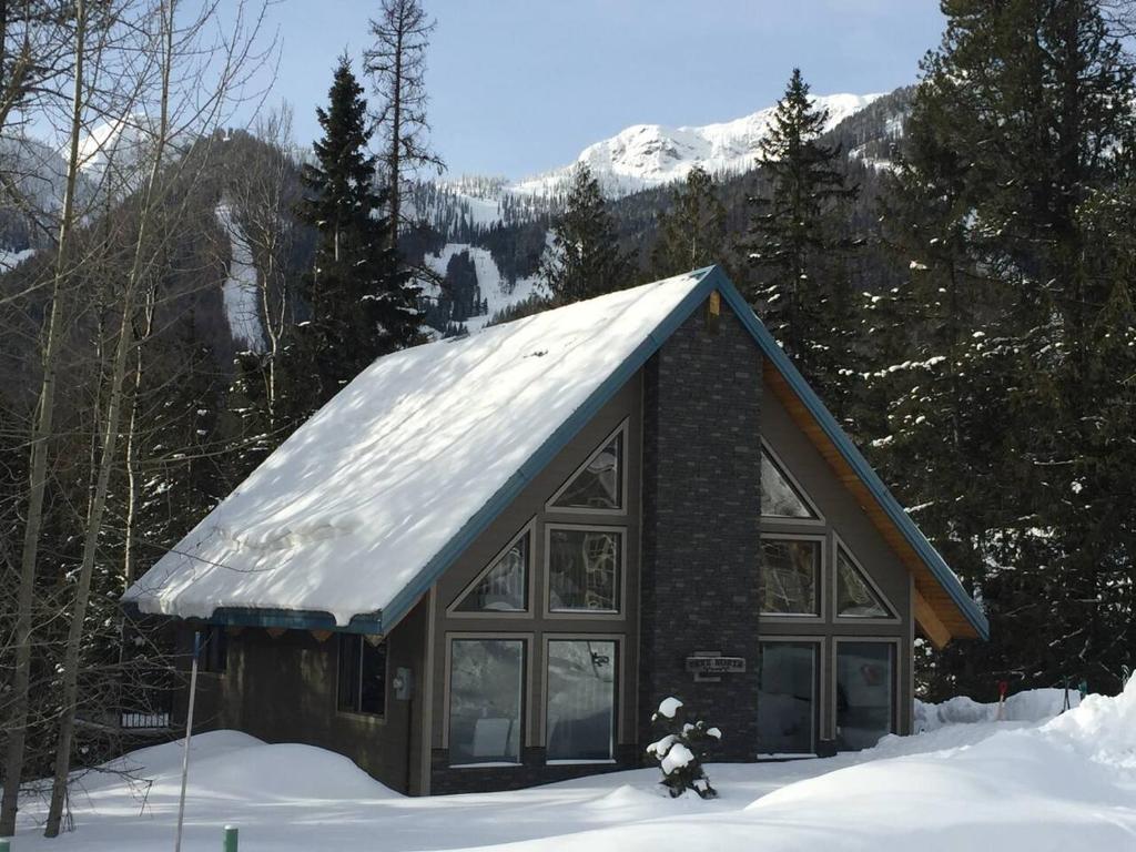 a building with a snow covered roof in the snow at Hot Tub Ski In 10 Min Walk to the Lifts in Fernie