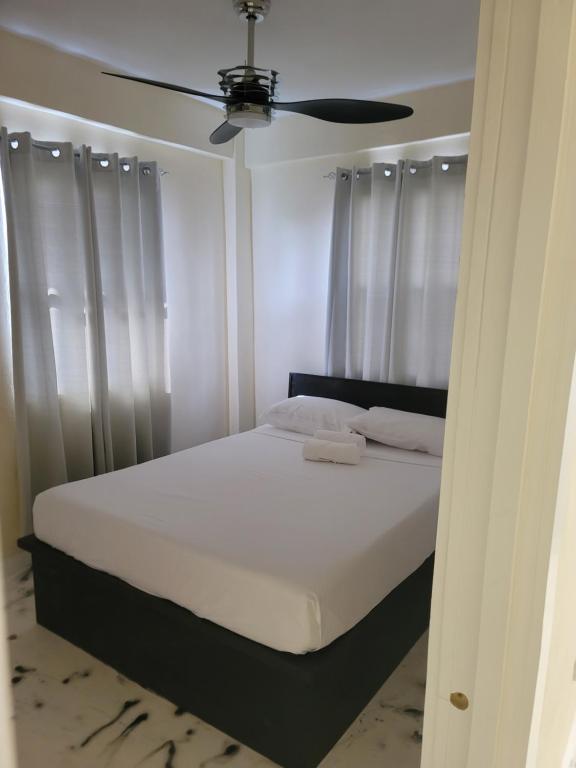 セントジョージズにあるVery comfortable in Townのベッドルーム1室(白いベッド1台、天井ファン付)