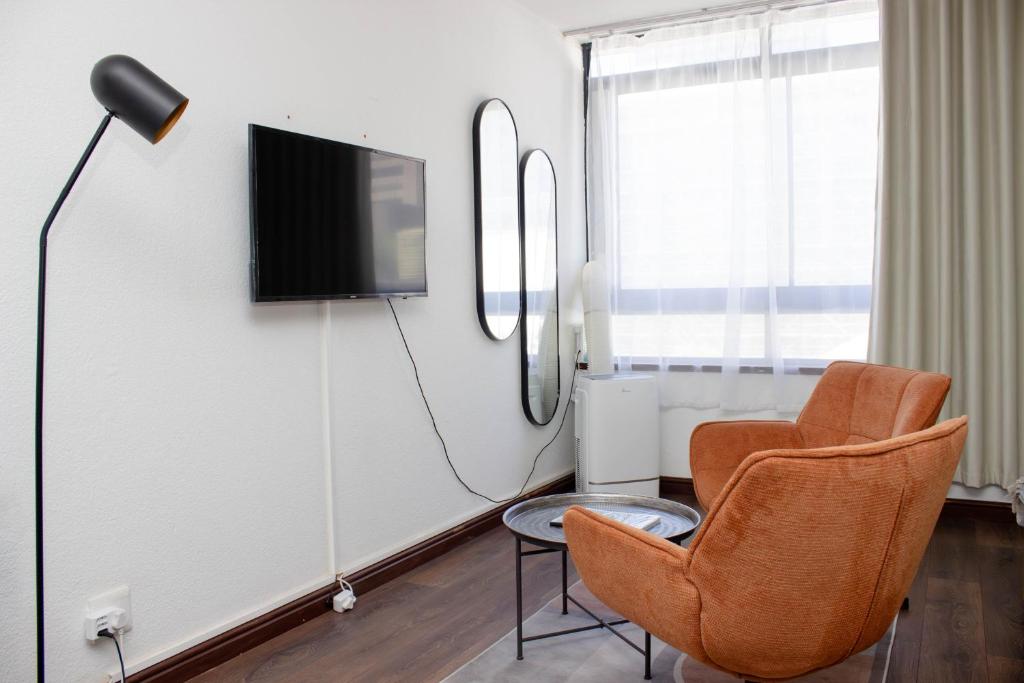 a living room with two chairs and a tv at The Diplomat Studio by Cape Living in Cape Town