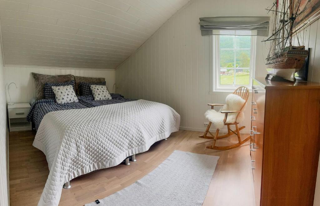 ein Schlafzimmer mit einem Bett und einem Stuhl und einem Fenster in der Unterkunft Coastal Cabin In Kastneshamn in Brostadbotn
