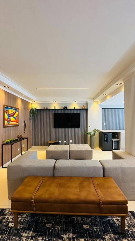 a living room with a large couch and a tv at Apartamento Guarujá, com sacada vista mar! Pé na areia, Lindo! in Guarujá