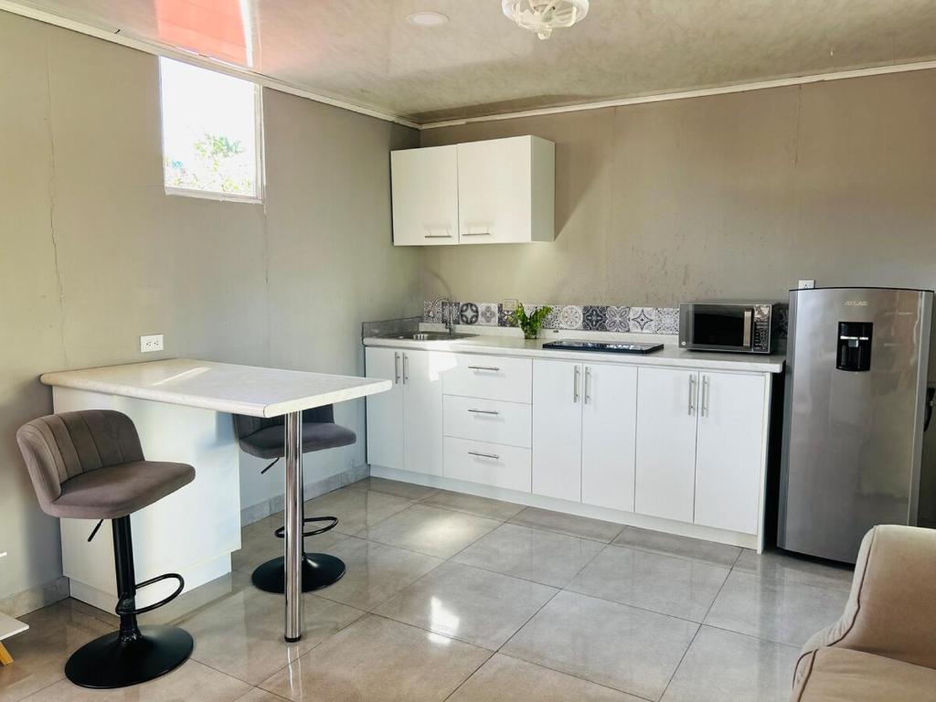 a kitchen with white cabinets and a table and a refrigerator at Apartamento Einoah in Puerto Limón