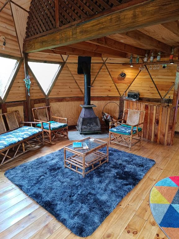 a living room with a fireplace in a log cabin at DOMO Ecológico in Curacautín